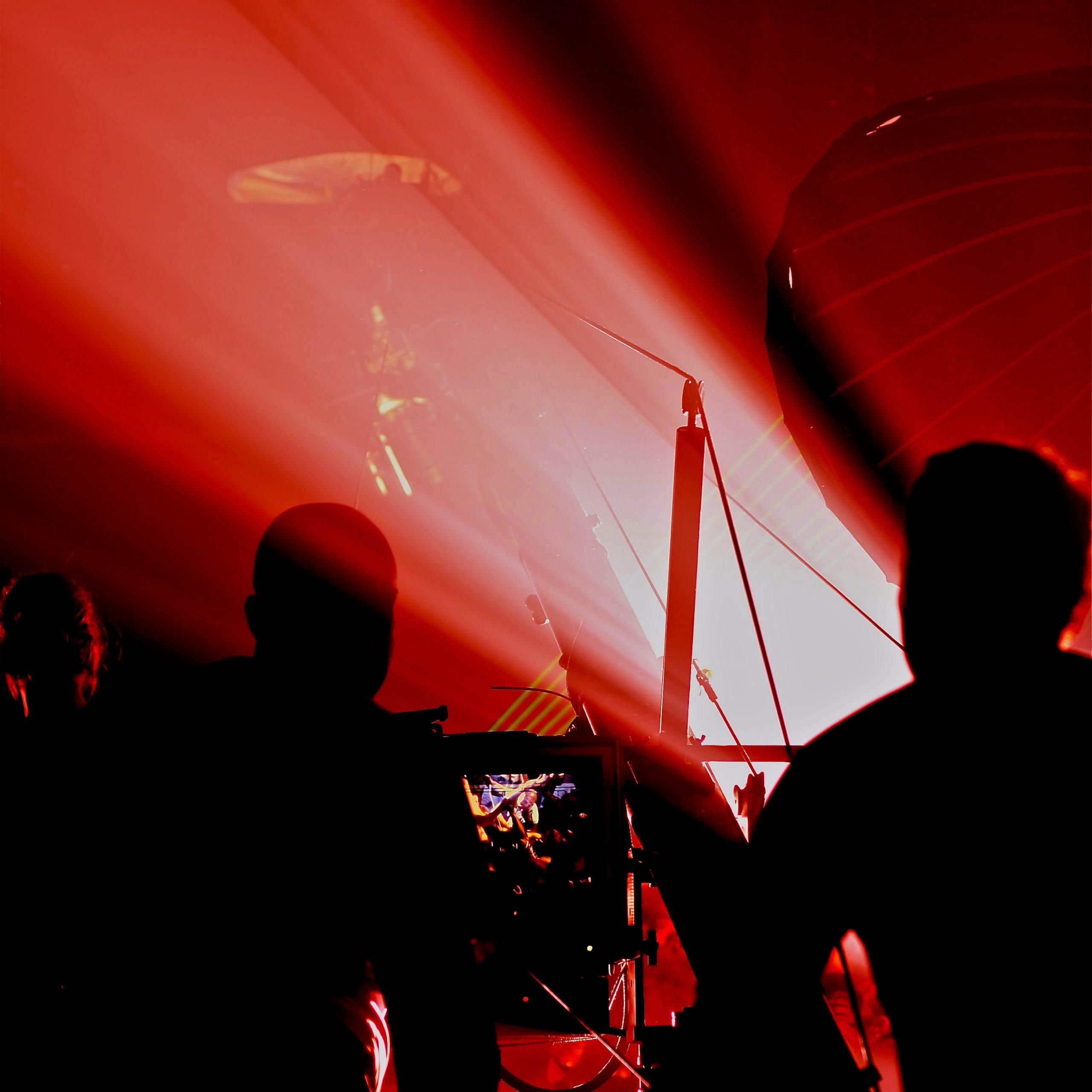 Silhouetted crew and jib against red laser lighting on the Alesha Dixon music video shoot