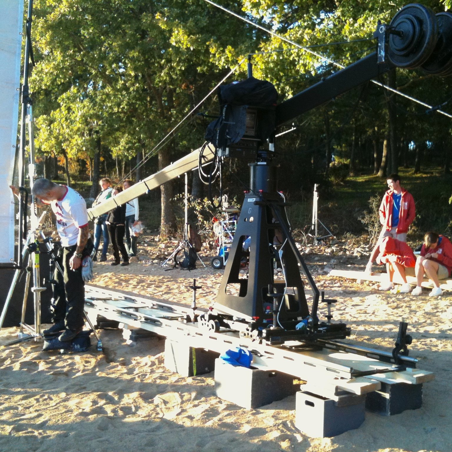 Jimmy Jib rigged on track over sand for an outdoor shoot, with cast and crew behind
